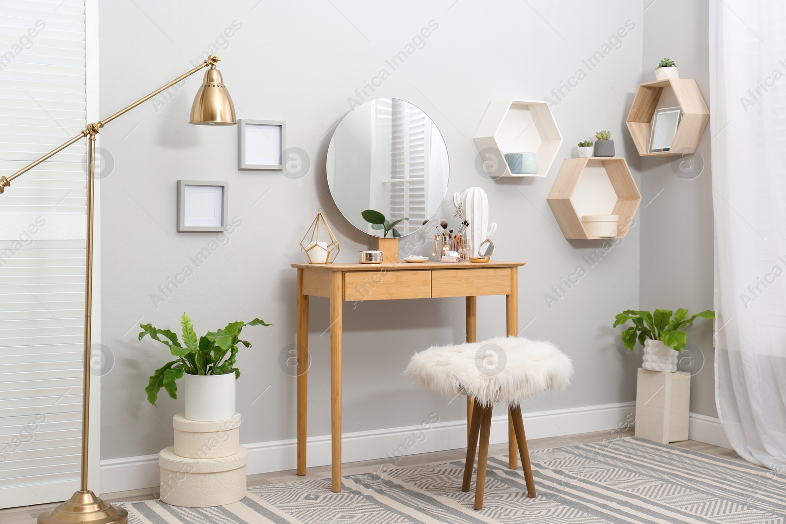 Photo of Stylish room interior with wooden dressing table and mirror on light wall