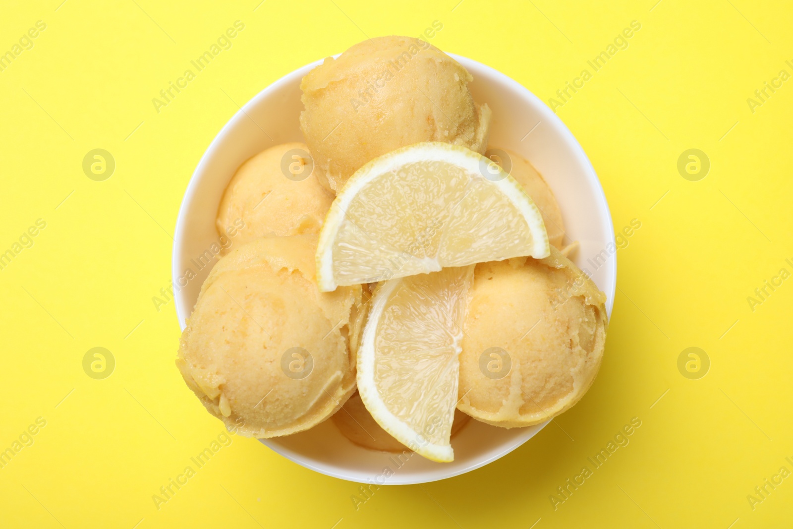 Photo of Delicious lemon ice cream on yellow background, top view
