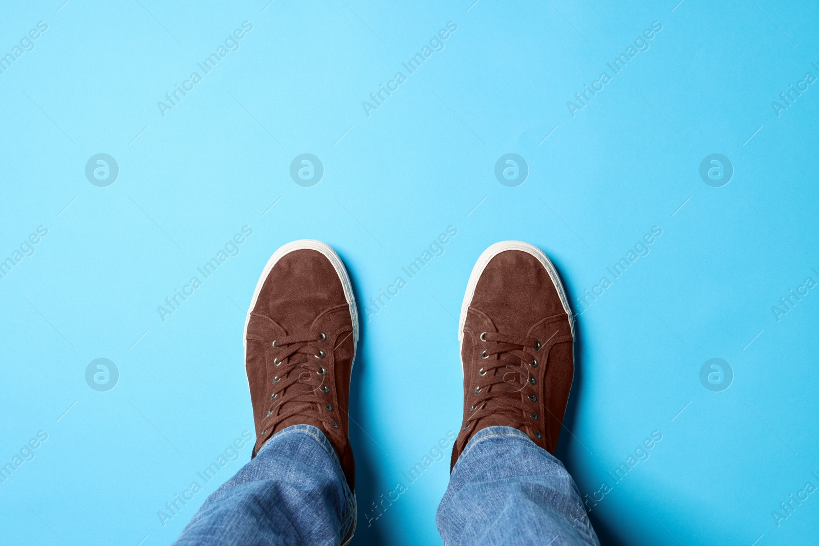 Photo of Man in brown shoes standing on light blue background, top view