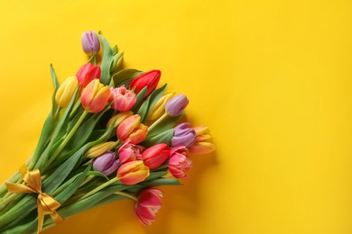 Bunch of beautiful tulips on yellow background, top view. Space for text