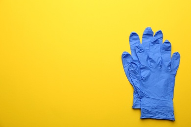 Photo of Pair of medical gloves on yellow background, flat lay. Space for text