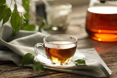 Photo of Tasty tea in cup on wooden table, closeup