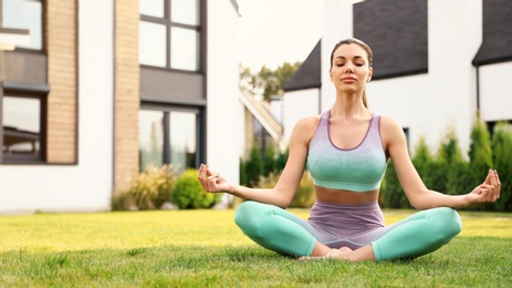 Photo of Woman practicing morning yoga at backyard. Healthy lifestyle