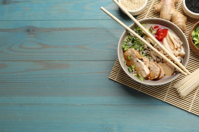 Photo of Delicious ramen with meat and ingredients on light blue wooden table, flat lay. Space for text