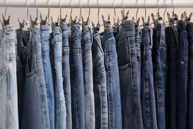 Photo of Rack with stylish jeans on color background, closeup