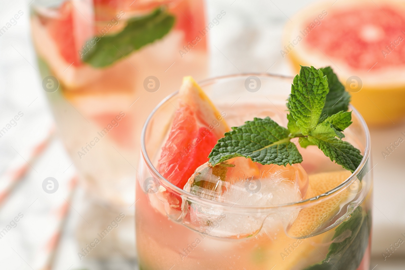 Photo of Glass of refreshing drink with grapefruit and mint on table, closeup view. Space for text