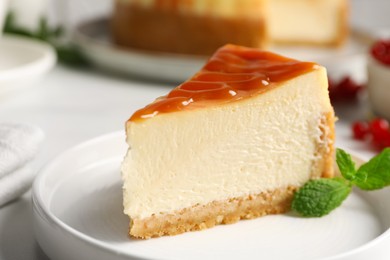 Photo of Piece of delicious caramel cheesecake served on white table, closeup