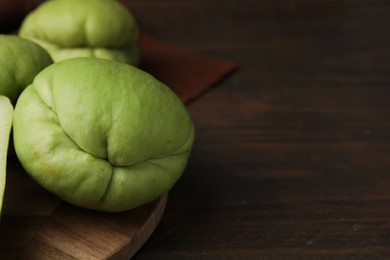 Fresh green chayote on wooden table, closeup. Space for text