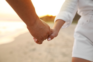 Photo of Lovely couple holding hands on beach, closeup
