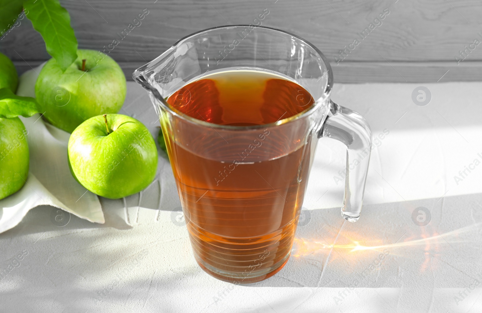 Photo of Jug with juice and fresh apples on table