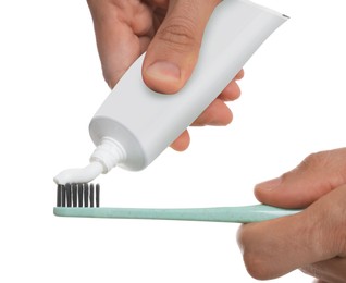 Man applying toothpaste on brush against white background, closeup