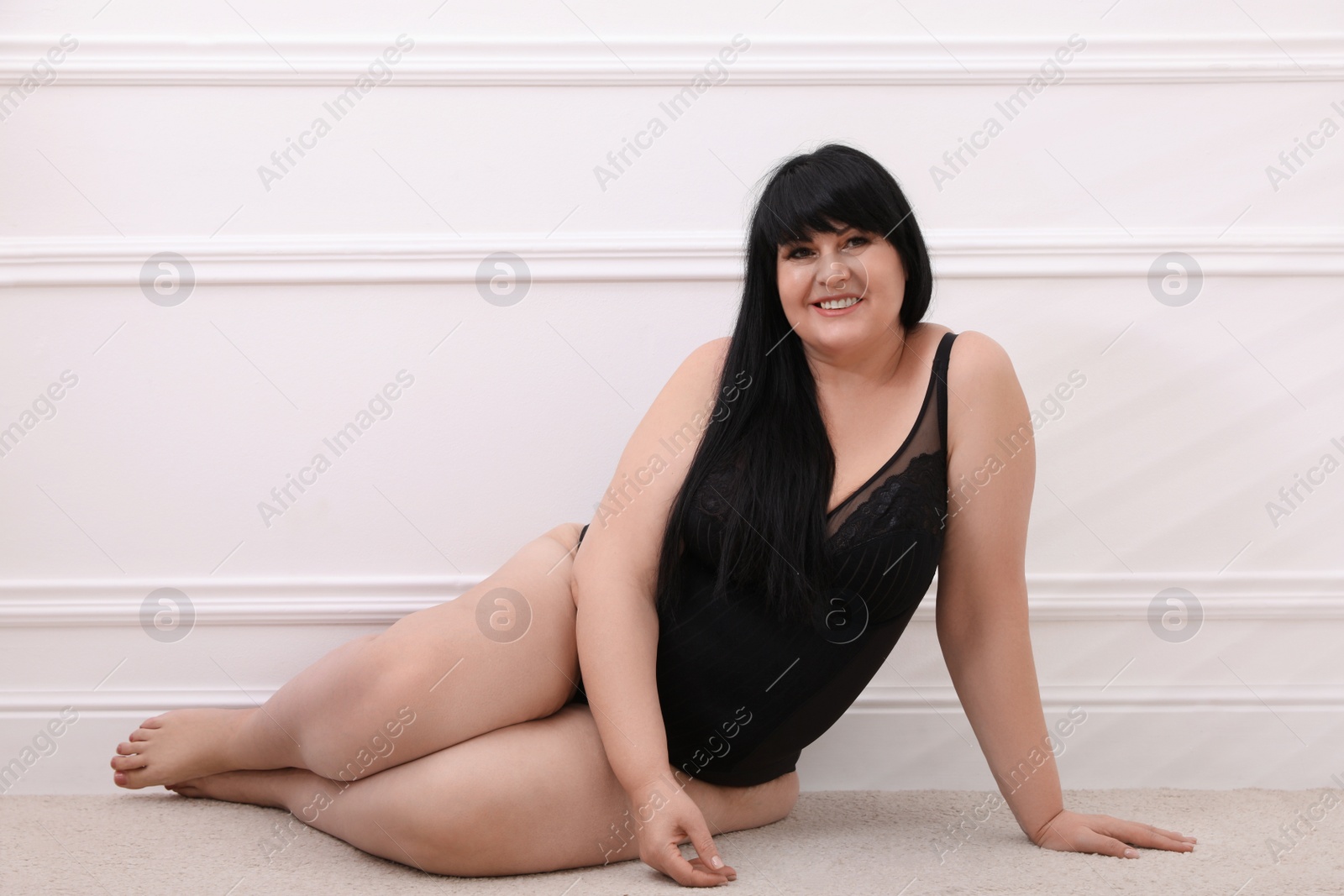 Photo of Beautiful overweight woman in black underwear posing at home. Plus-size model