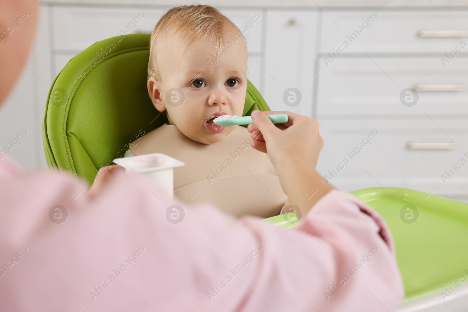 Photo of Mother feeding her cute little baby with healthy food at home