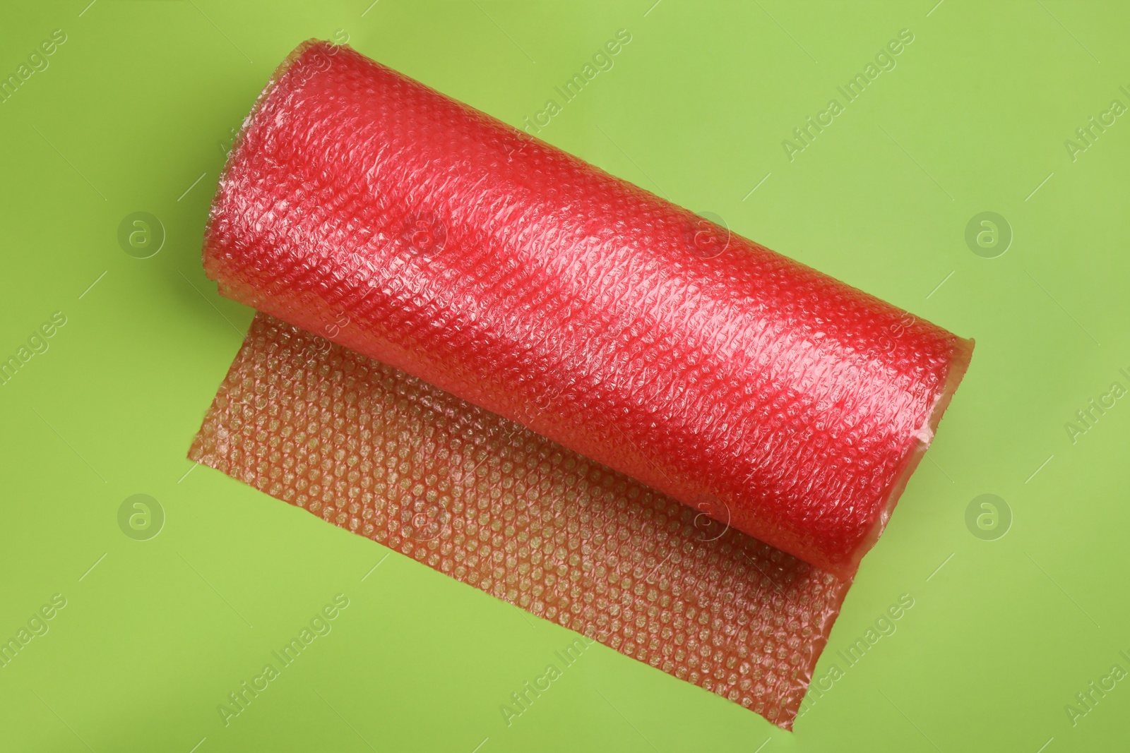 Photo of Bubble wrap roll on green background, top view