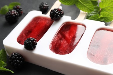 Tasty berry ice pops in mold on grey table, closeup. Fruit popsicle
