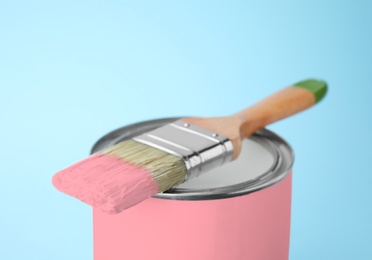 Can of pink paint with brush on blue background