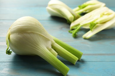 Photo of Whole and cut fennel bulb on light blue wooden table, closeup