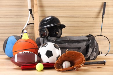 Many different sports equipment on wooden table