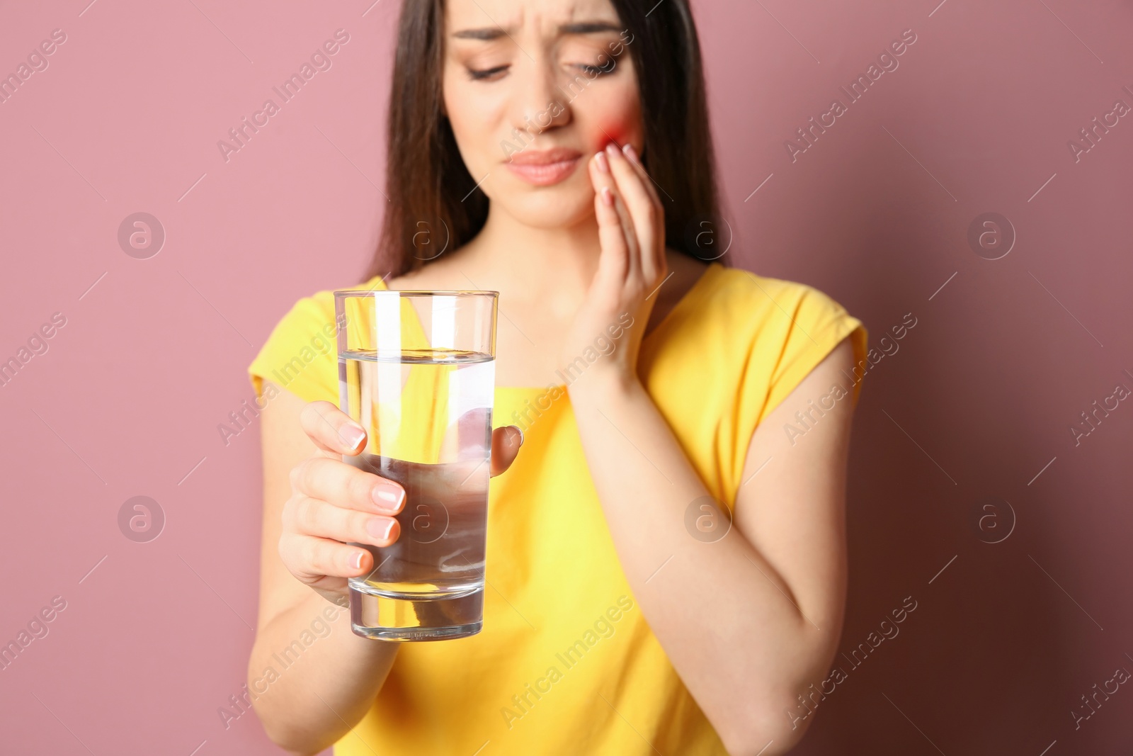 Photo of Woman with sensitive teeth holding glass of water on color background