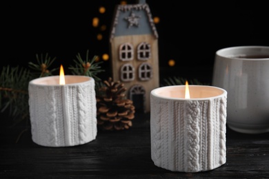 Photo of Composition with candles in ornate holders on wooden table. Christmas decoration