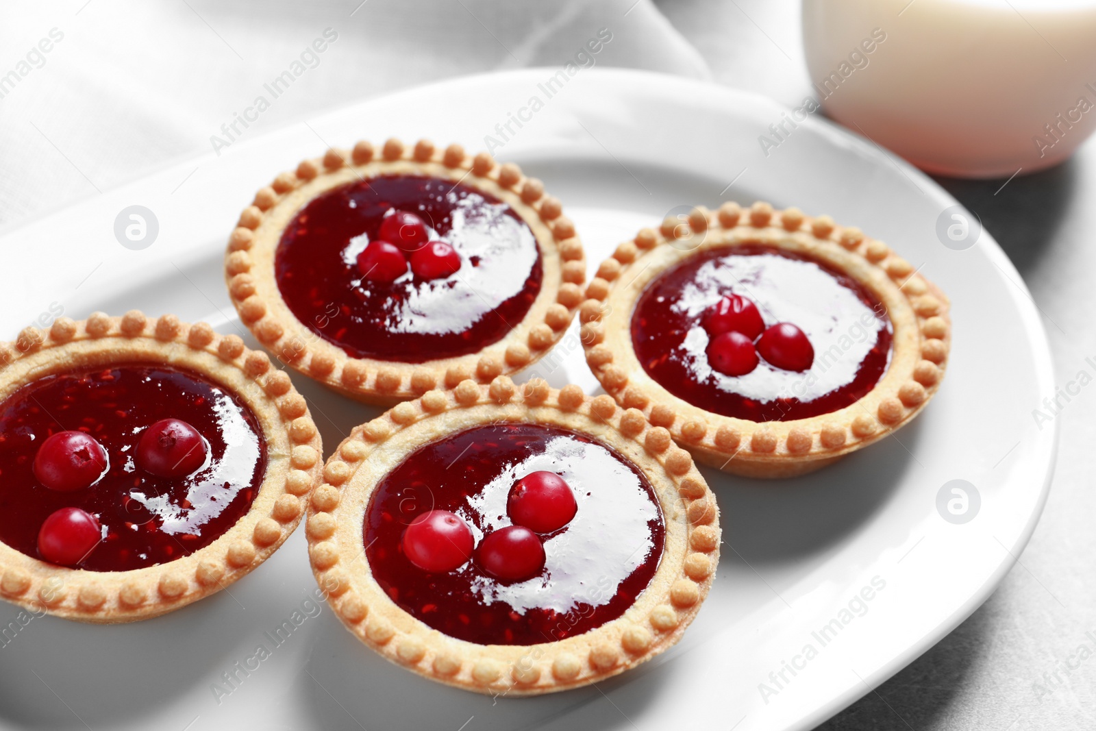 Photo of Tasty tartlets with jam on plate, closeup