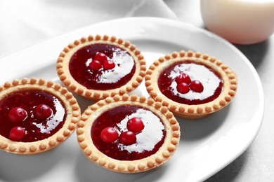 Photo of Tasty tartlets with jam on plate, closeup