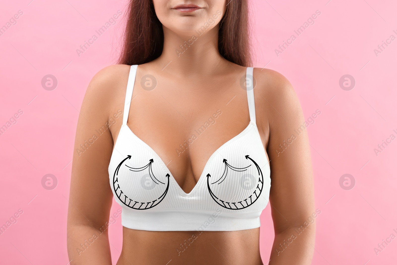 Image of Breast surgery. Woman with markings on bra against pink background, closeup