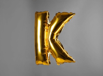 Photo of Golden letter K balloon on grey background