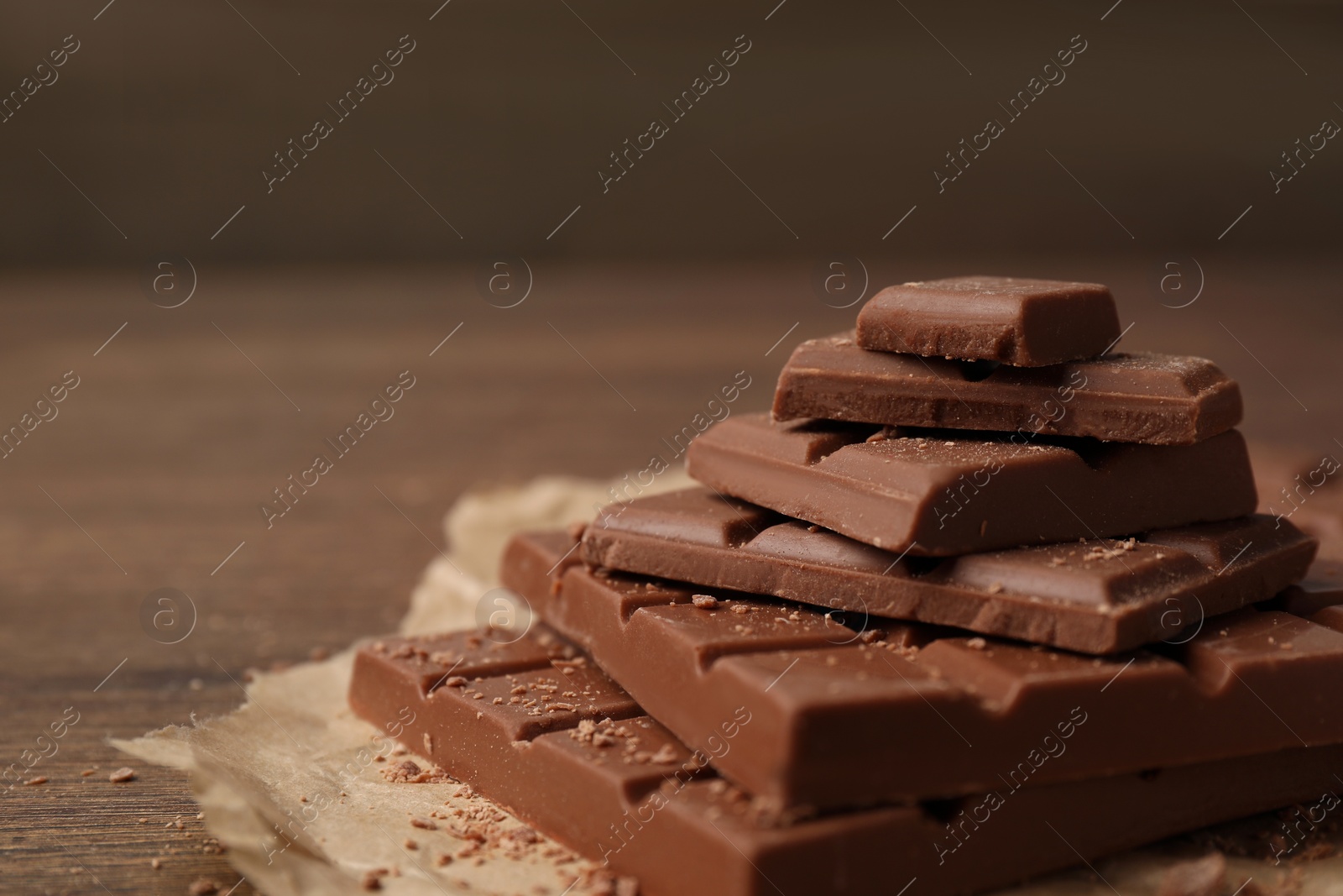 Photo of Pieces and crumbs of tasty chocolate on wooden table, closeup. Space for text