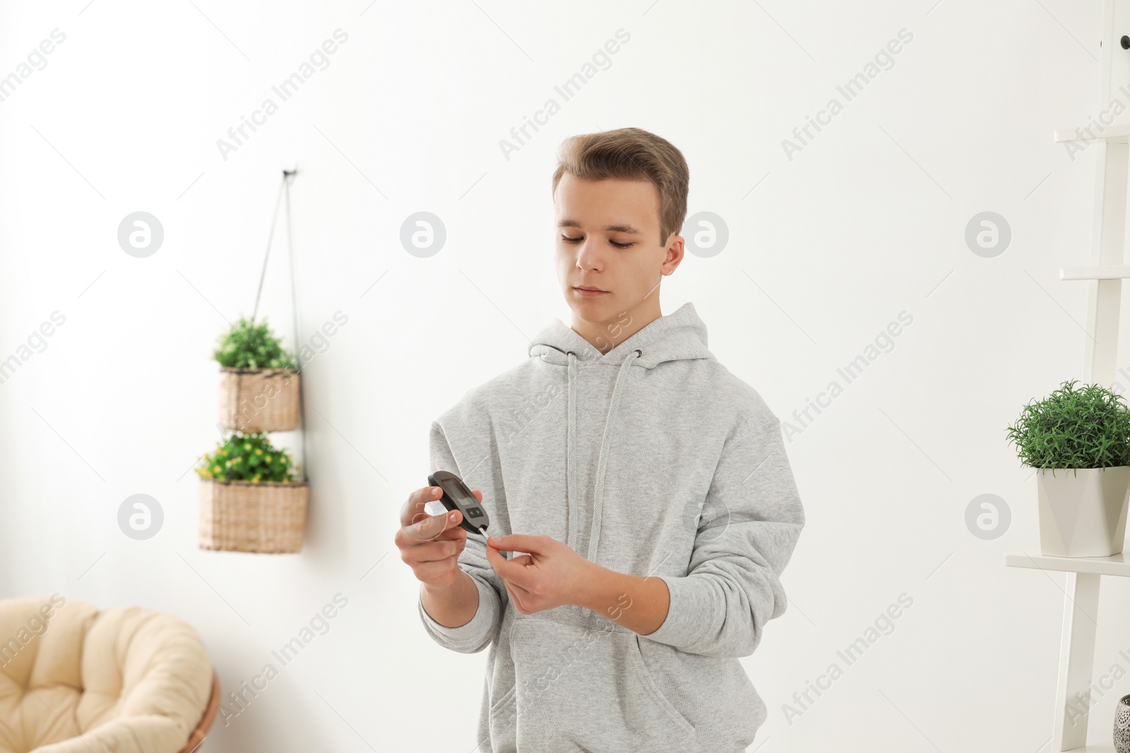 Photo of Teen boy holding digital glucometer at home. Diabetes control