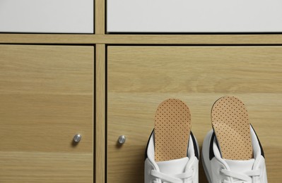 Orthopedic insoles in shoes near drawer, space for text