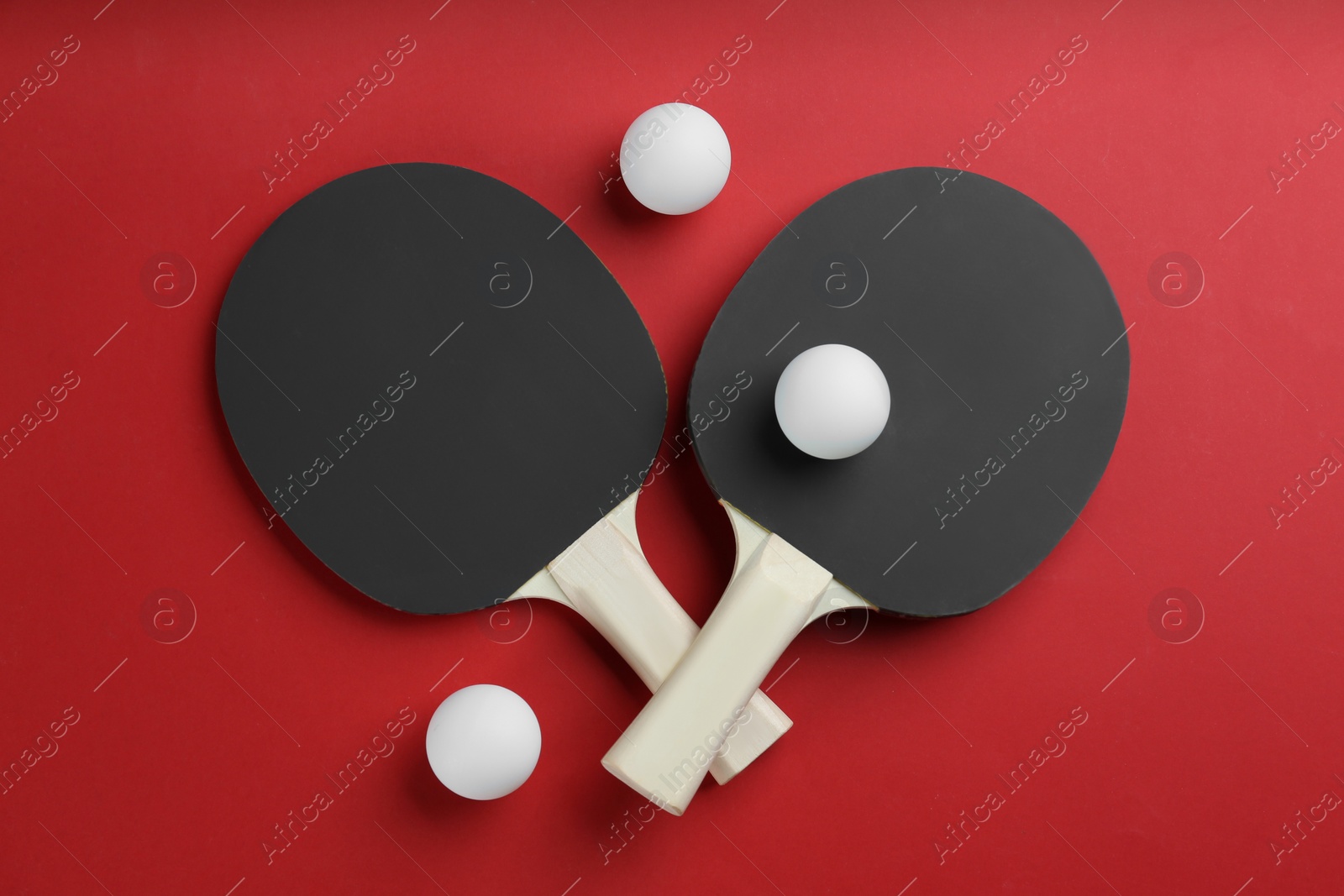 Photo of Ping pong rackets and balls on red background, flat lay