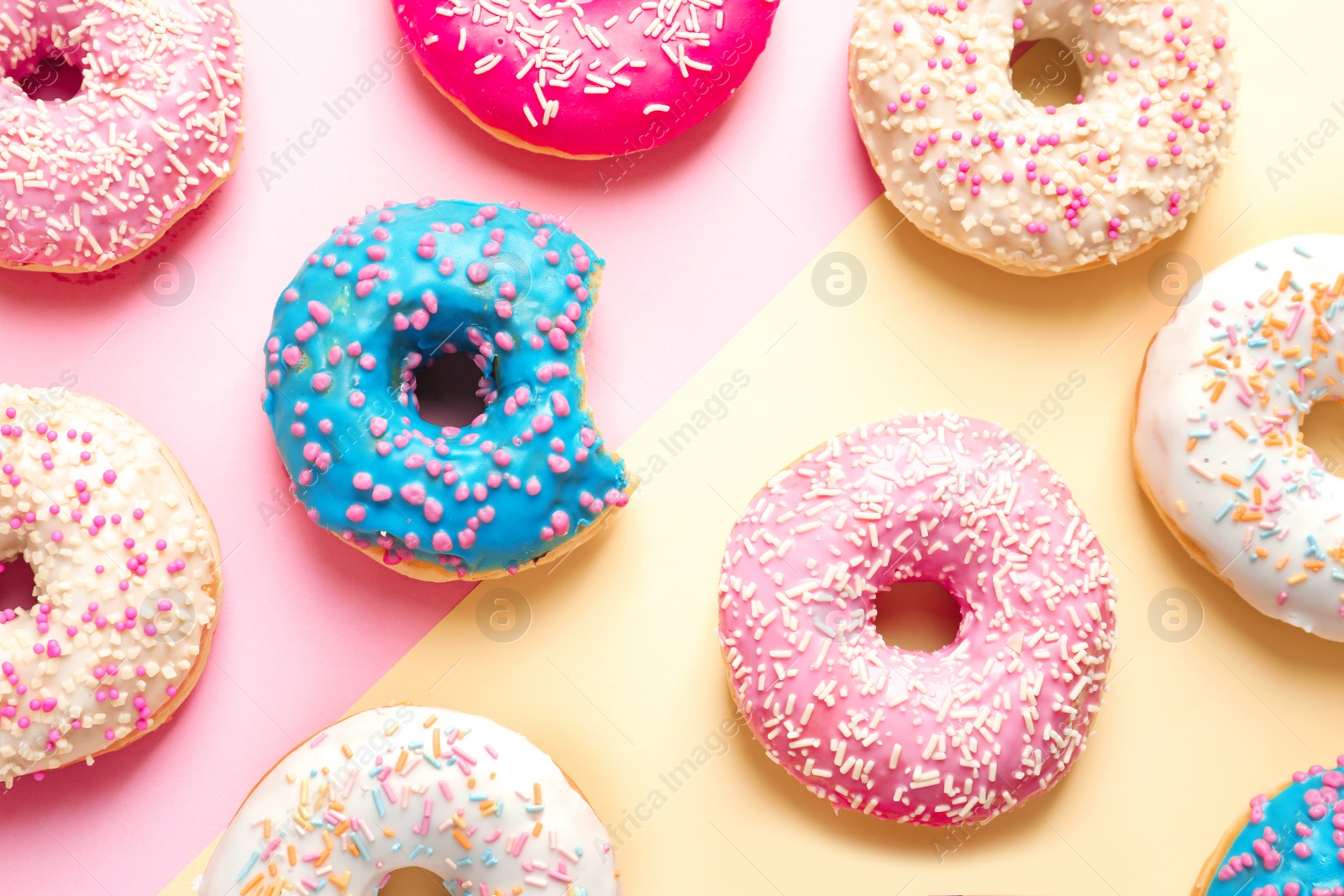 Photo of Delicious glazed doughnuts on color background, top view