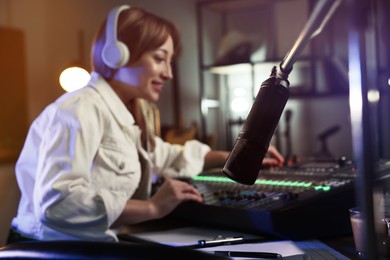 Woman working as radio host in modern studio, focus on microphone. Space for text