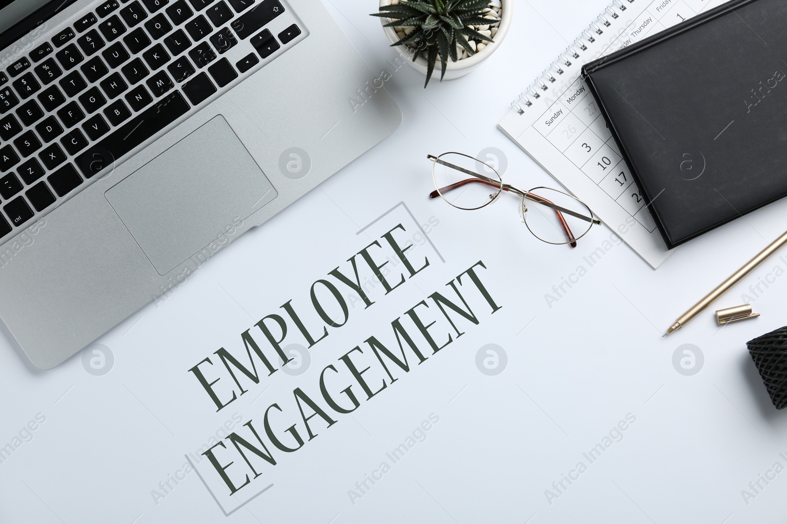 Image of Laptop, stationery and text EMPLOYEE ENGAGEMENT on white background, flat lay