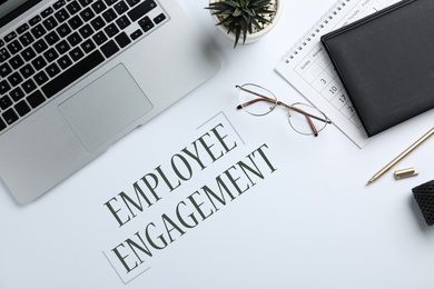 Laptop, stationery and text EMPLOYEE ENGAGEMENT on white background, flat lay