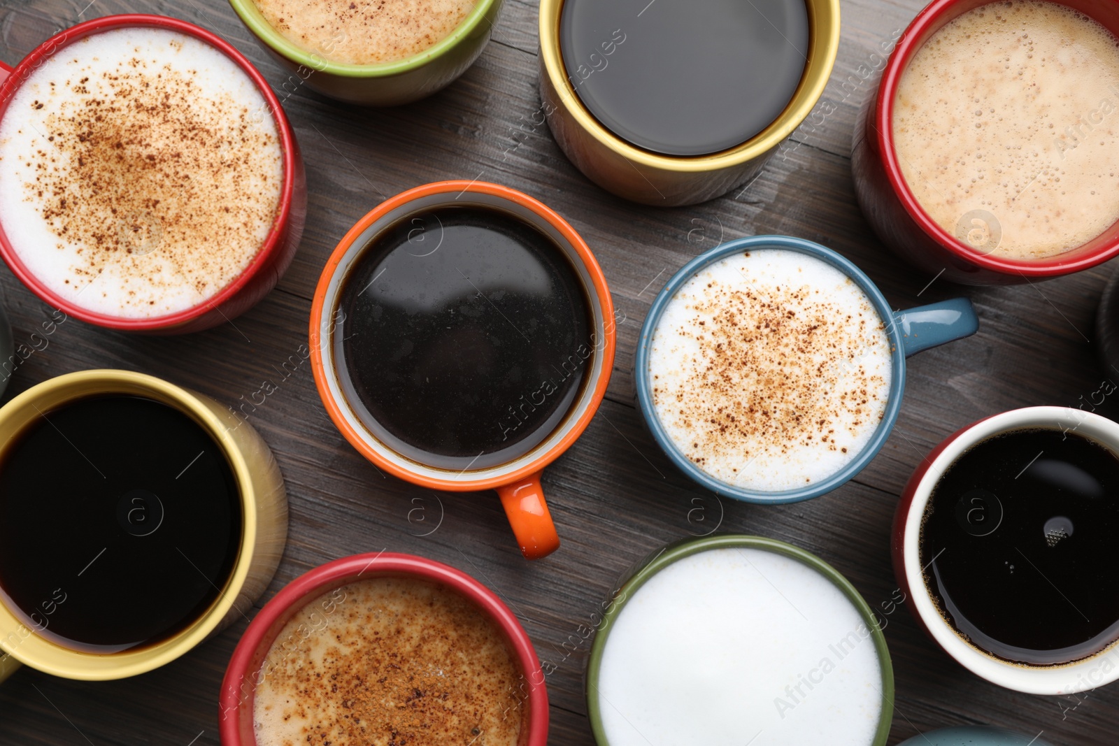 Photo of Many different cups with aromatic hot coffee on wooden table, flat lay