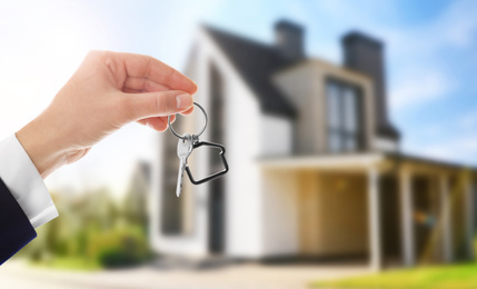 Image of Woman with key near new modern house outdoors, closeup