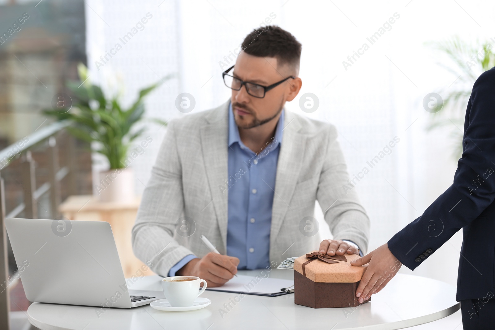 Photo of Woman giving bribe to man at table indoors