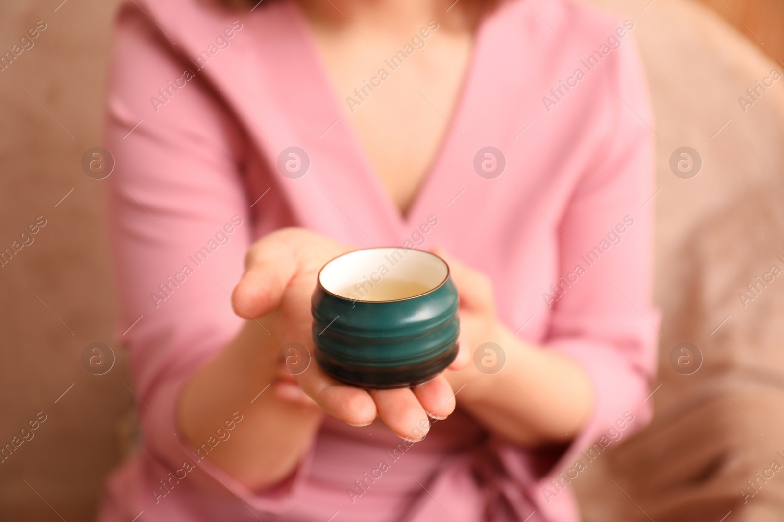 Photo of Master offering cup of freshly brewed tea during traditional ceremony, closeup