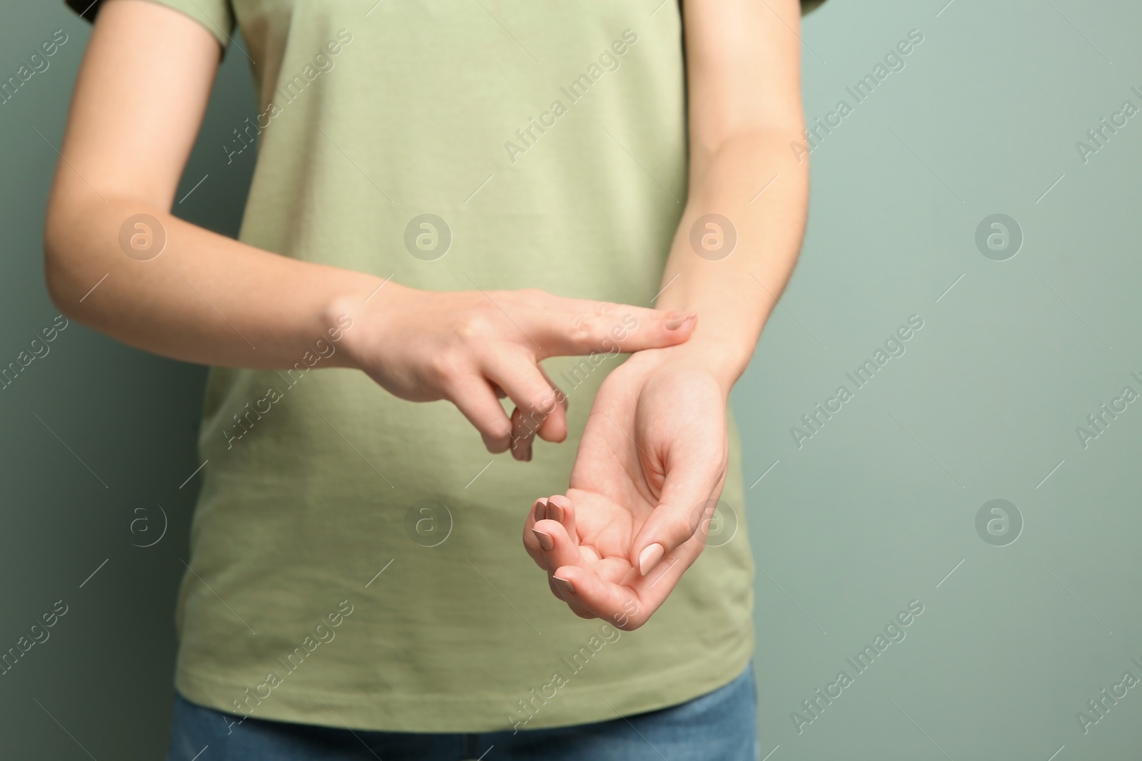 Photo of Young woman checking pulse on color background