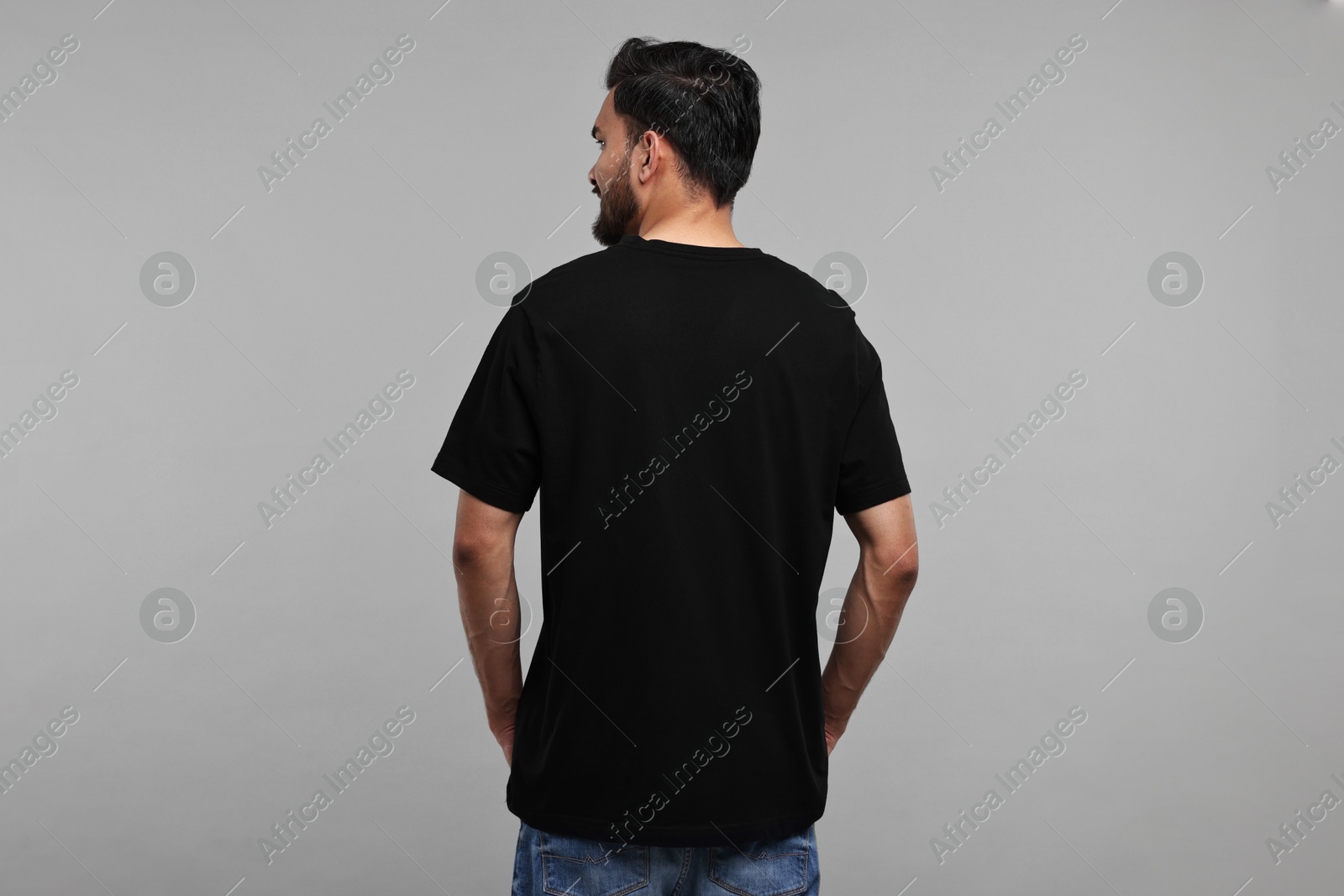 Photo of Man in black t-shirt on grey background, back view