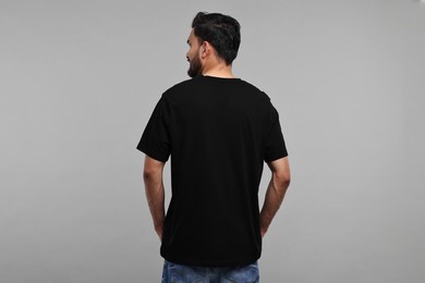 Photo of Man in black t-shirt on grey background, back view