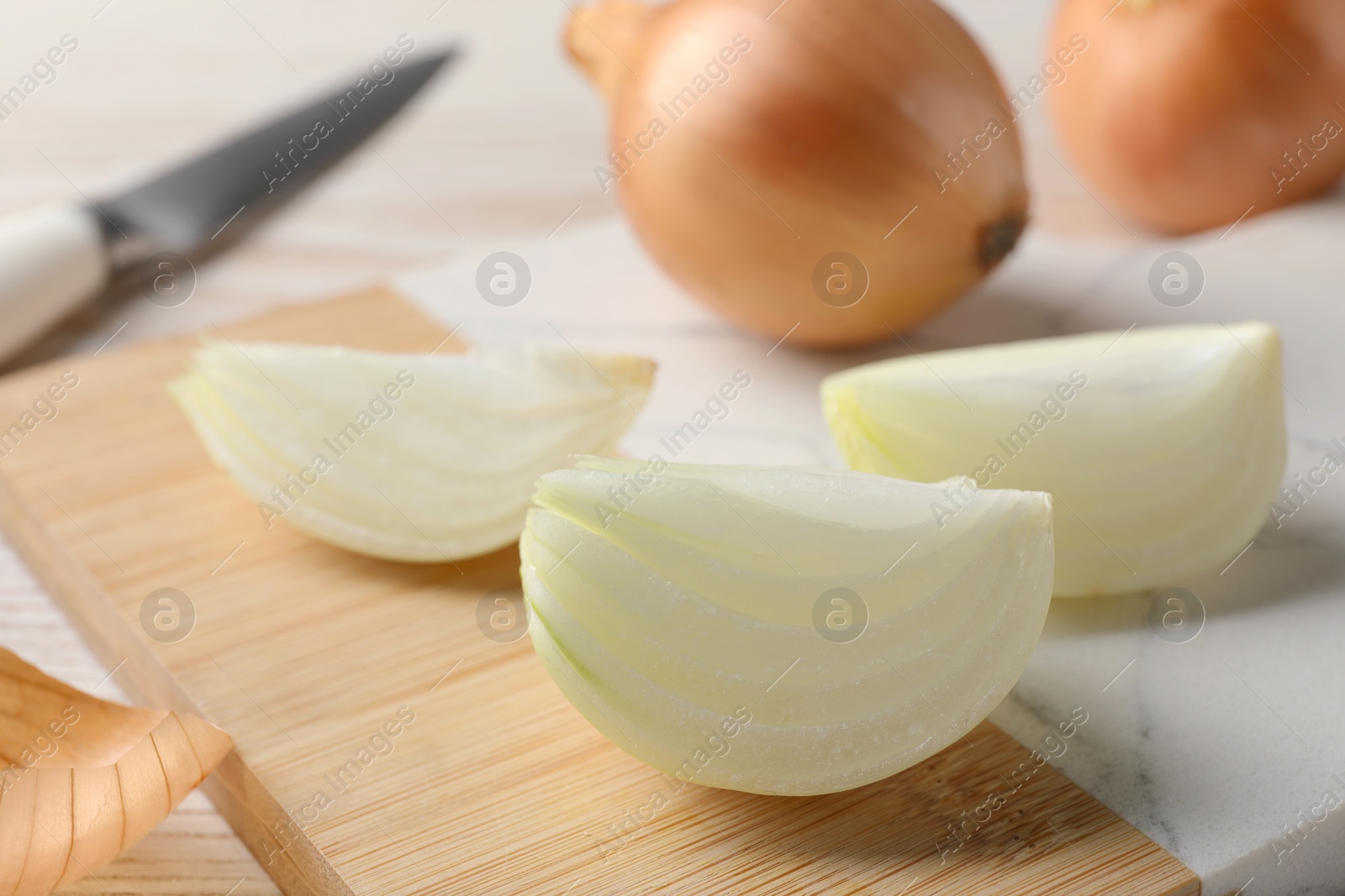 Photo of Whole and cut onions on white table, closeup