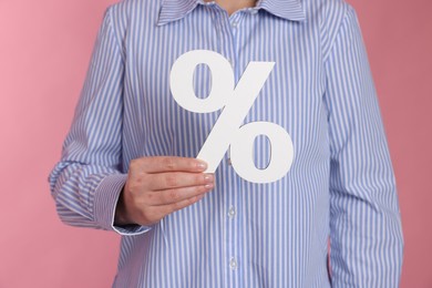 Photo of Woman holding percent sign on pink background, closeup