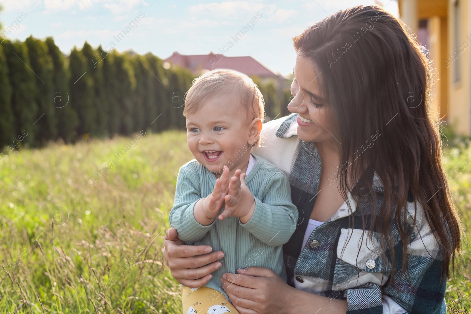 Photo of Happy mother with her cute baby at backyard on sunny day, space for text