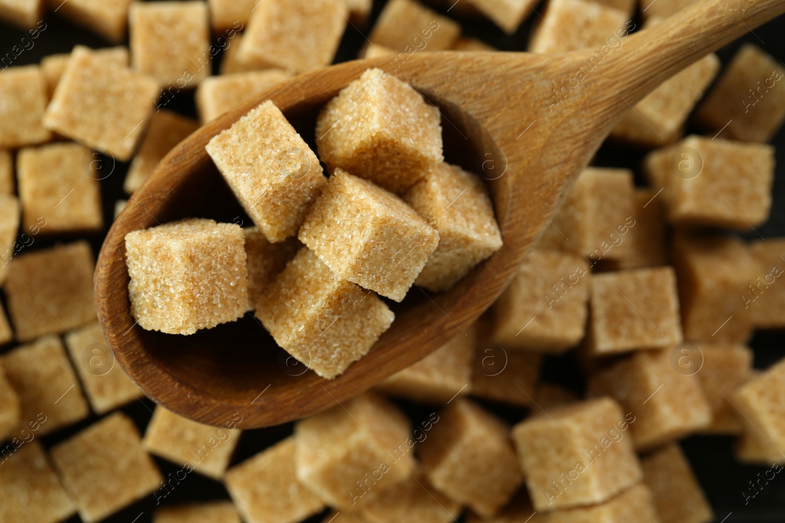 Photo of Spoon with brown sugar cubes over table, top view