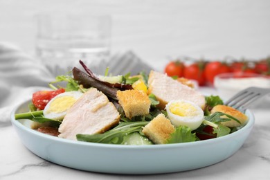 Photo of Delicious salad with croutons, chicken and eggs served on white marble table, closeup