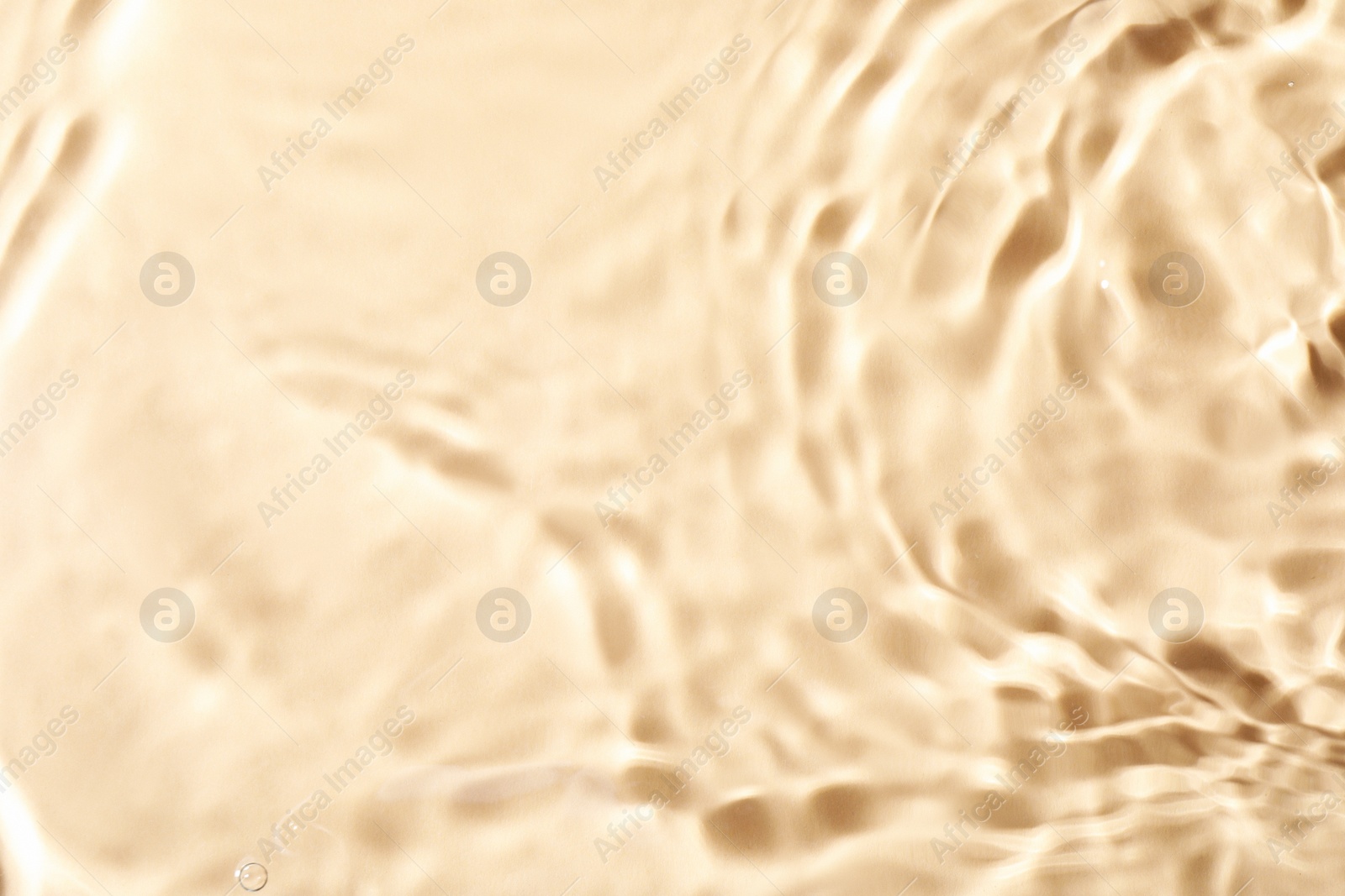 Photo of Closeup view of water with rippled surface on beige background