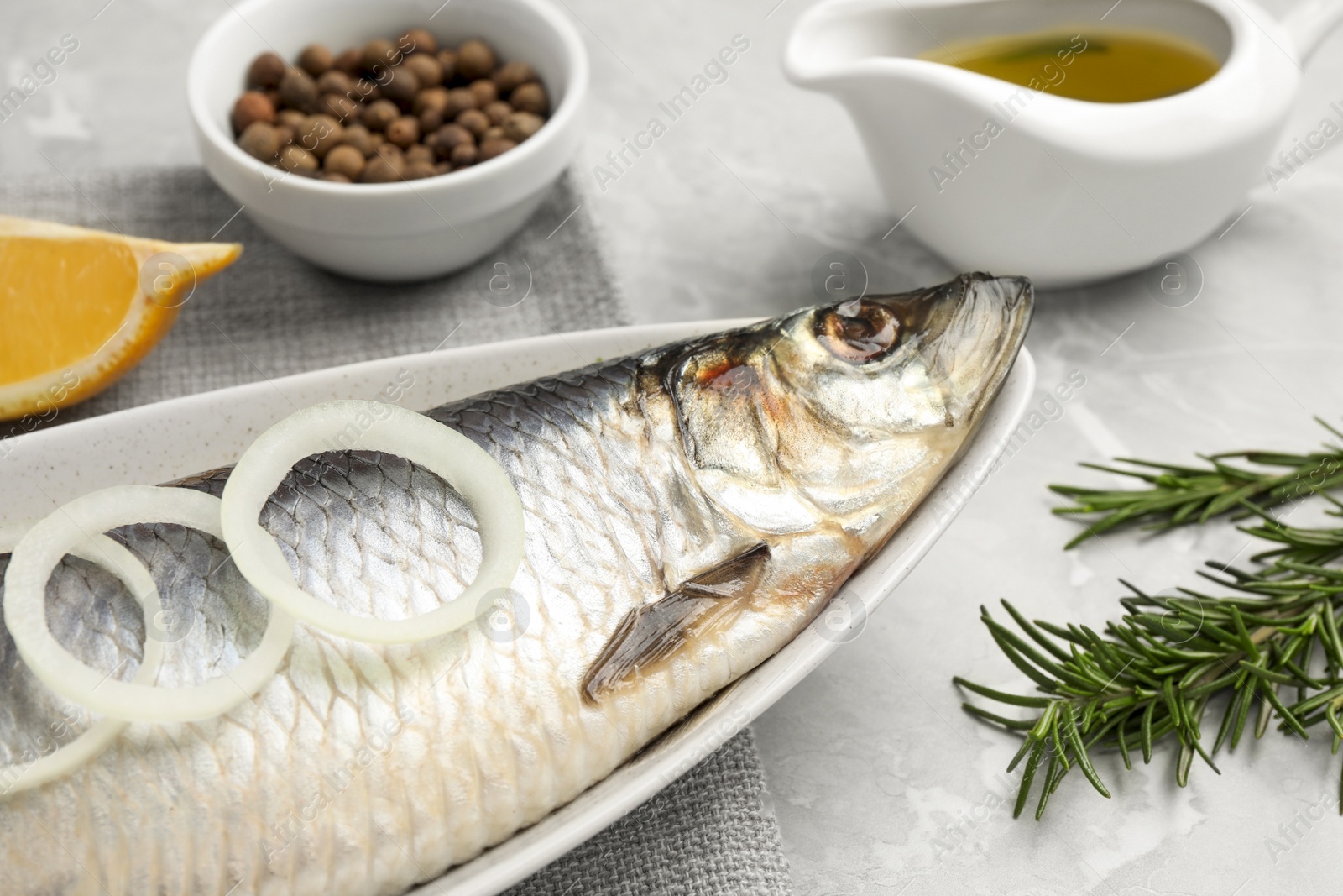 Photo of Delicious salted herring and ingredients on light grey table, closeup